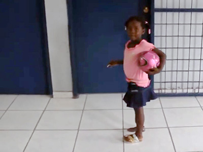 Little Haitan girl playing football with prosthetic leg